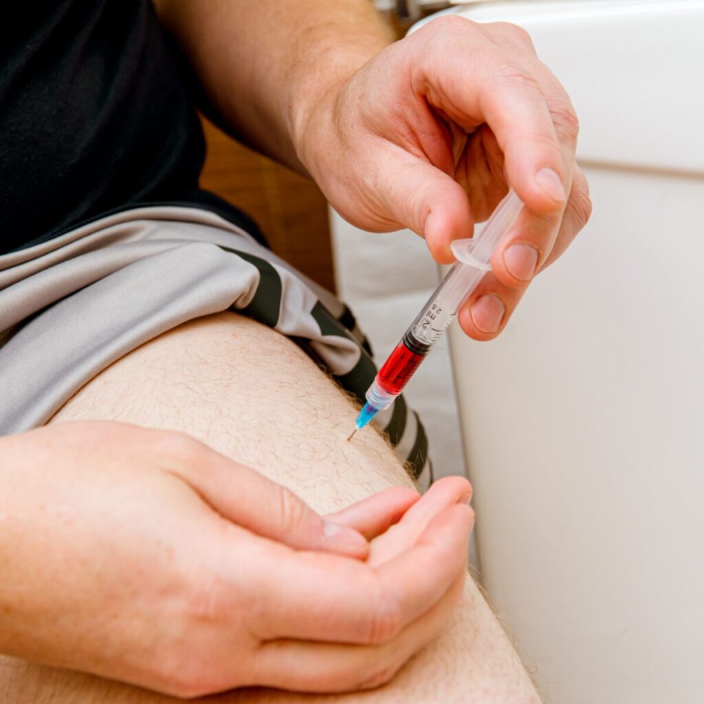 Person injecting b12 into his leg.