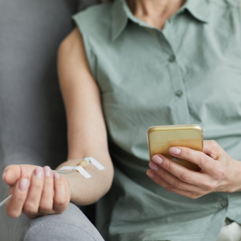 Woman getting IV drip while holding phone.