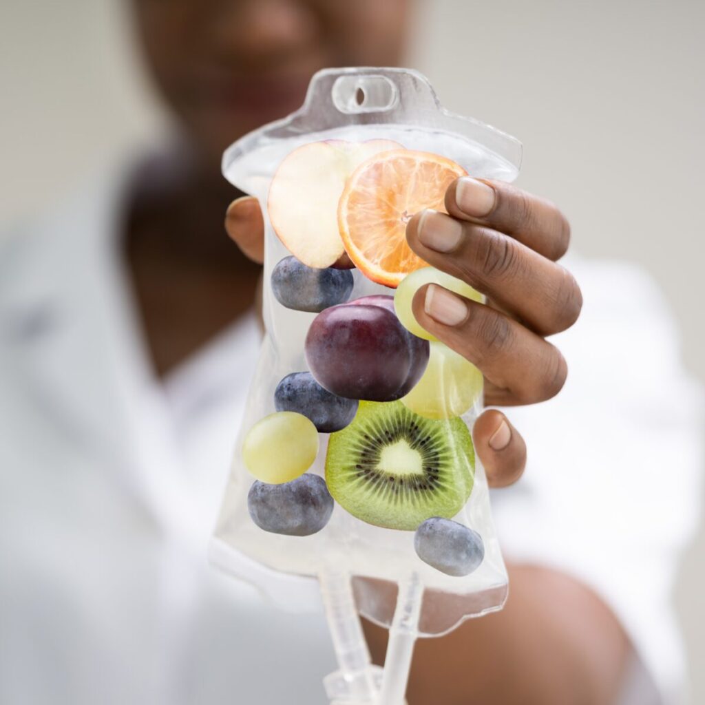Woman holding IV drip with illustration of different fruits.