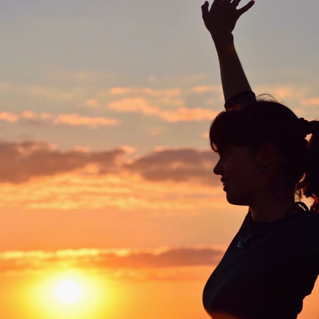 Woman dancing with sun in the background.
