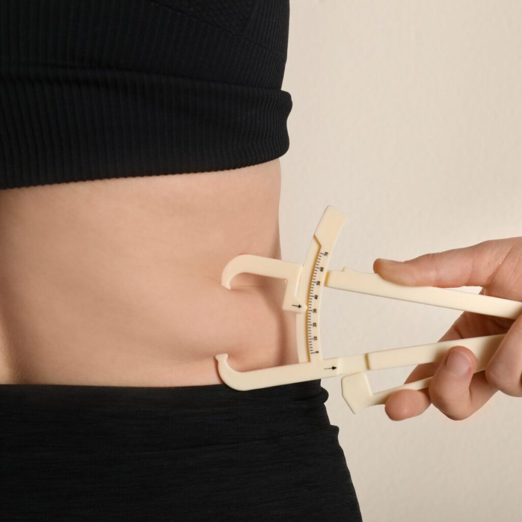 Body fat in the waist being measured with caliper.
