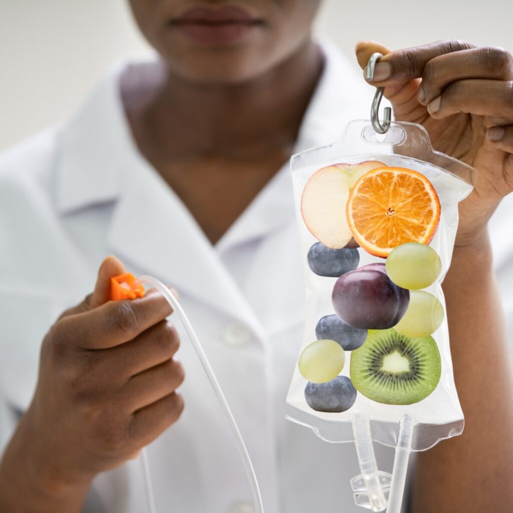 Woman holding IV bag with fruits representing vitamins.