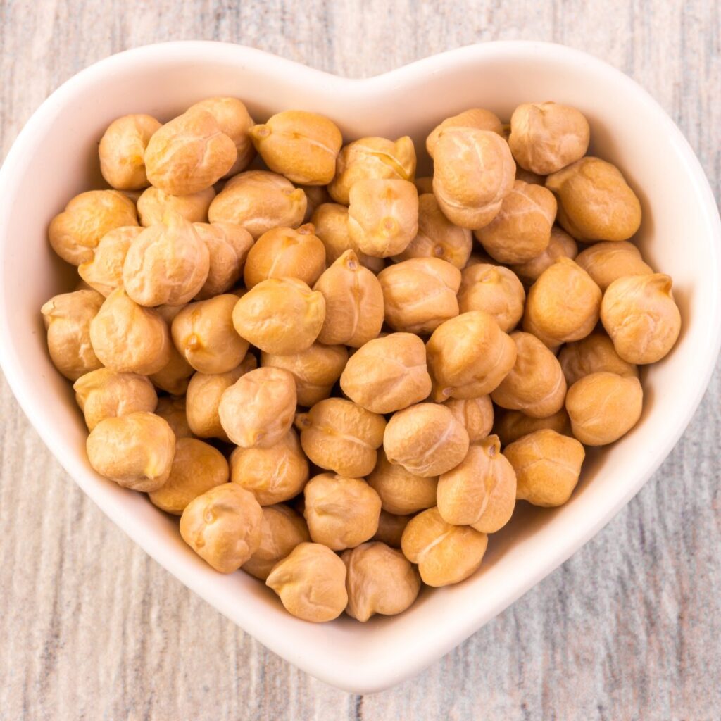 chickpeas on a heart shaped bowl on a table.