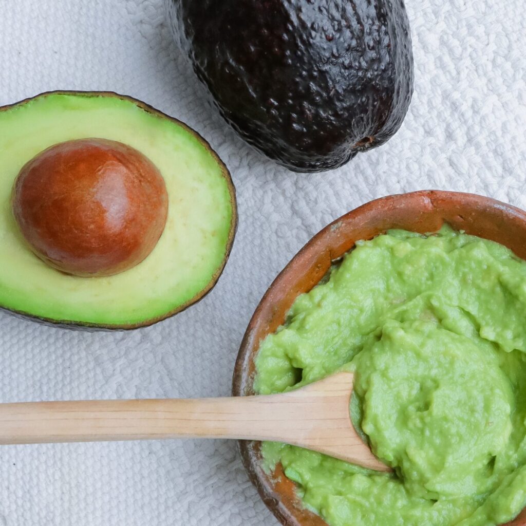 Avocado and bowl of guacamole on a table.