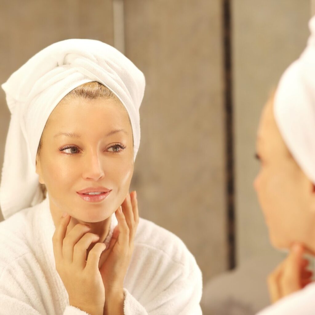 Woman looking at the mirror while touching her face.