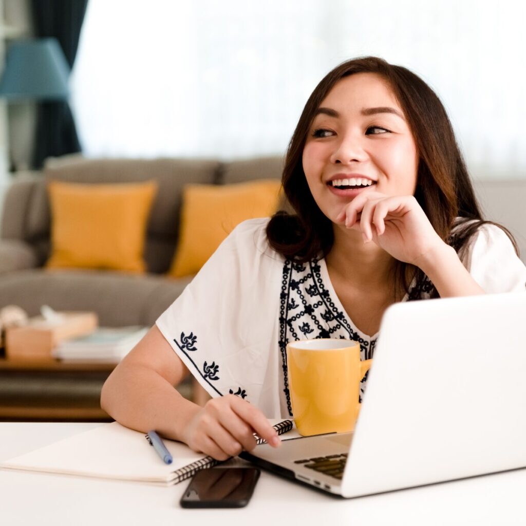Woman smiling in front of a laptop.