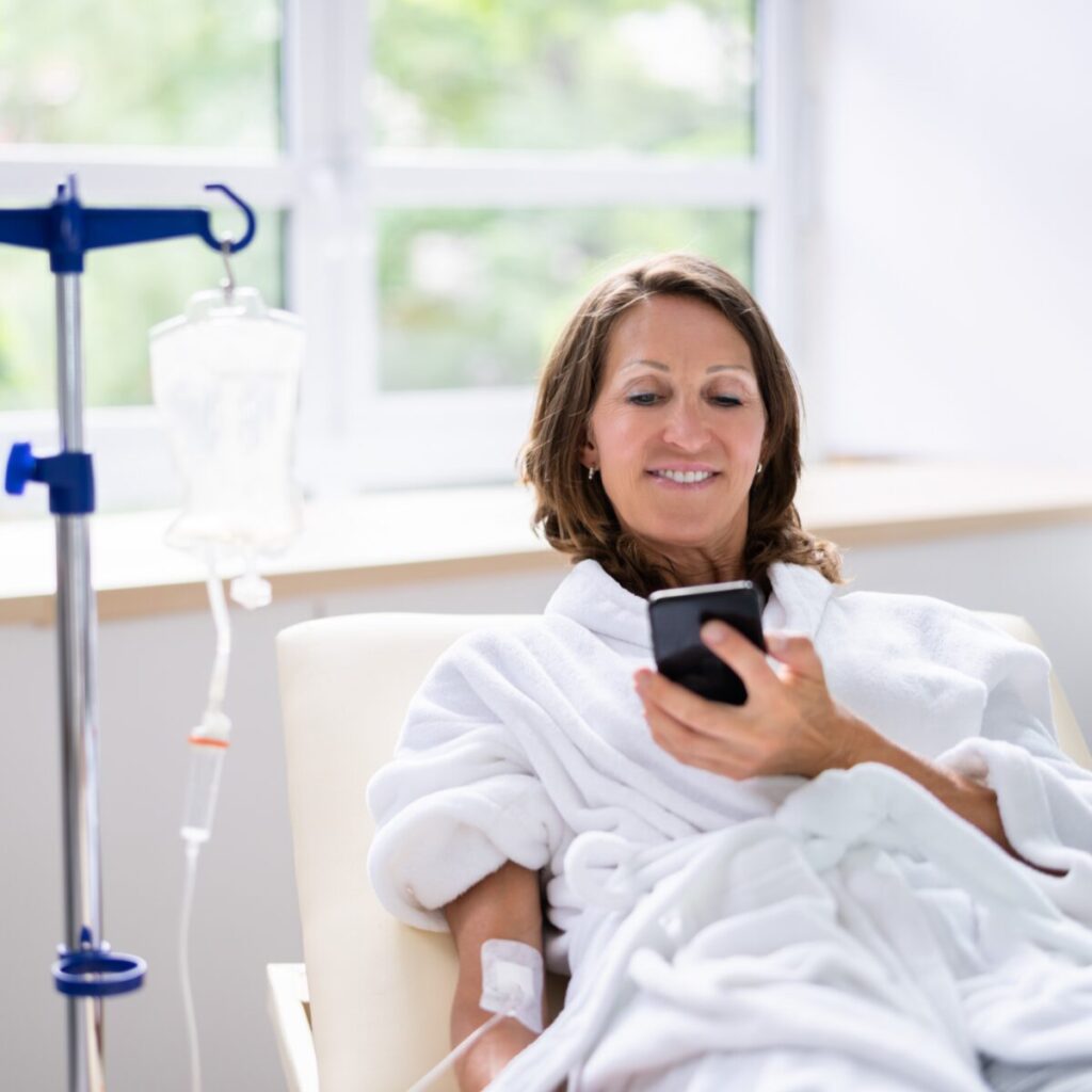 Woman getting an IV treatment while using phone.