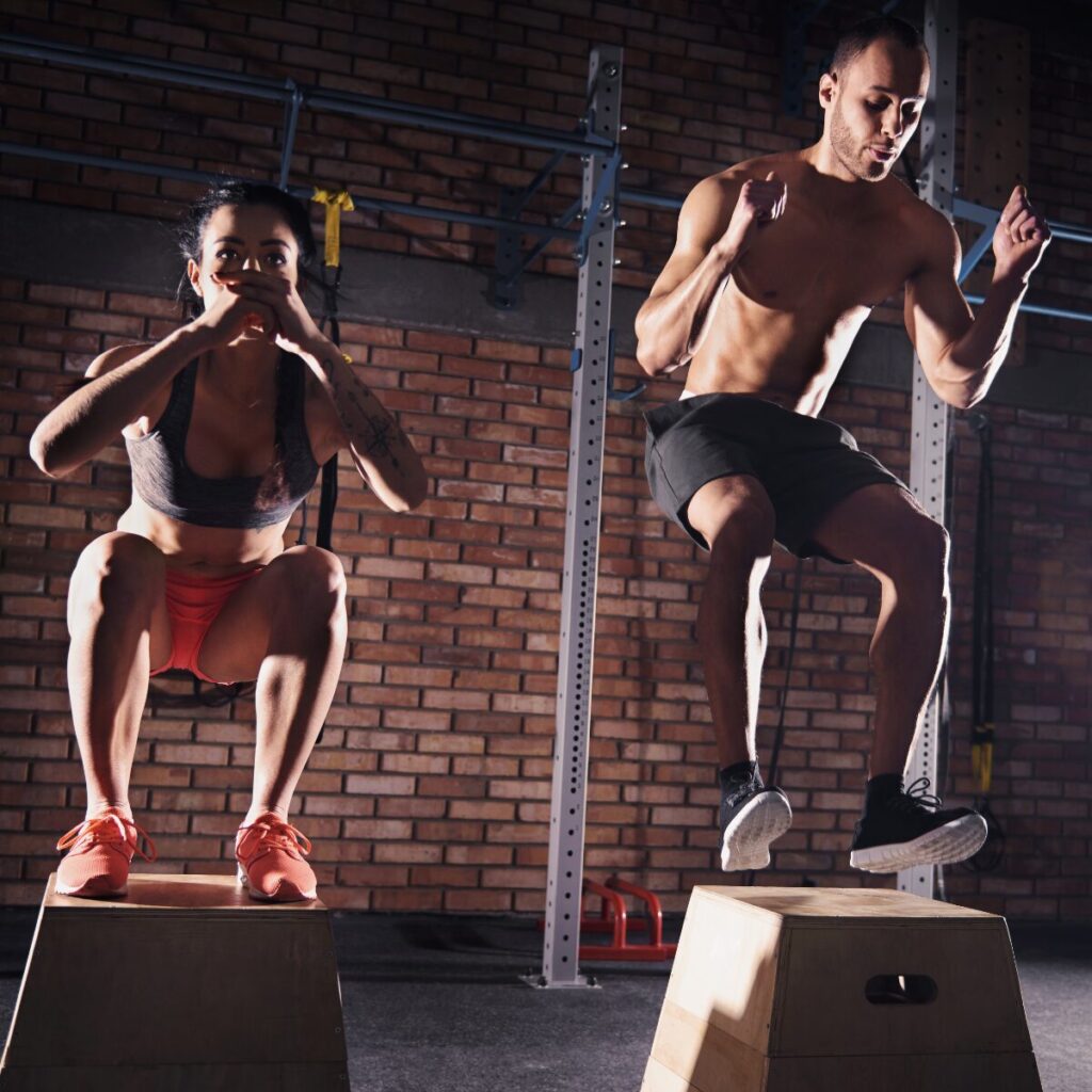 Man and woman doing box jumps during Crossfit training.
