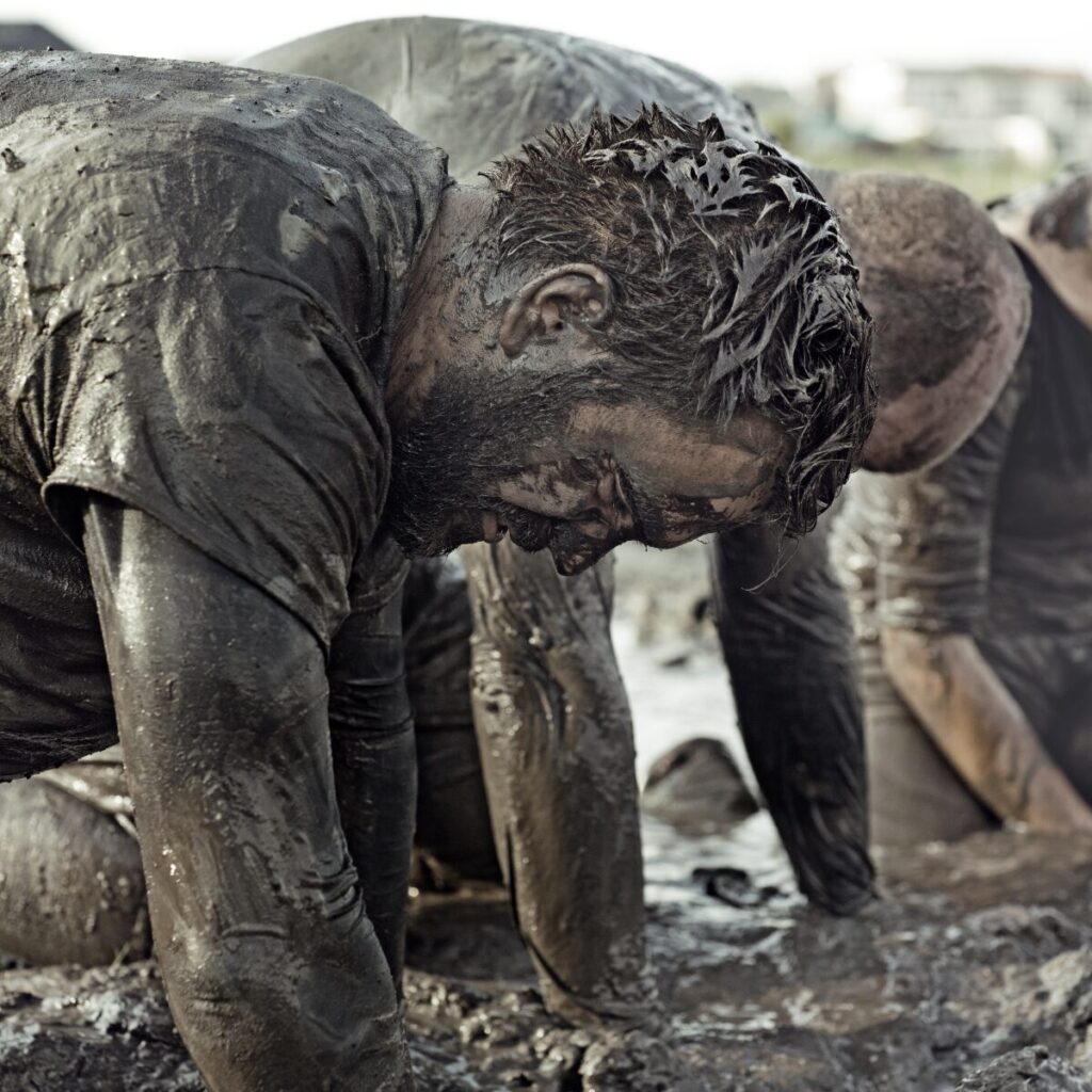 Man tired after running mud obstacle course.