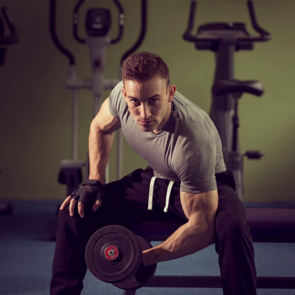 Man sitting on a bench doing bicep curls.