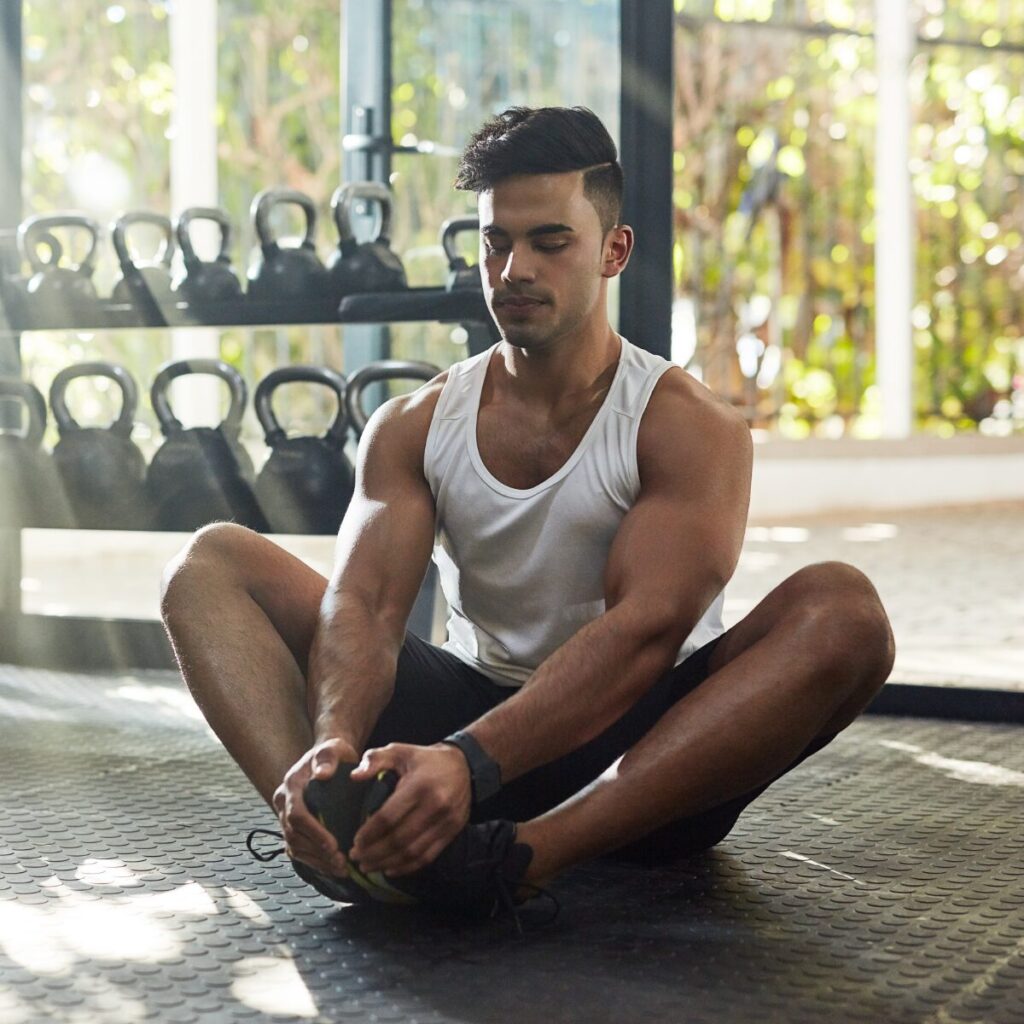 Man sitting on the floor doing pre-workout prep.