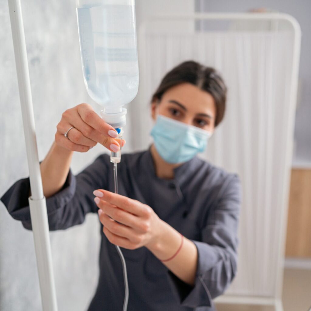 Nurse adjusting IV drip.