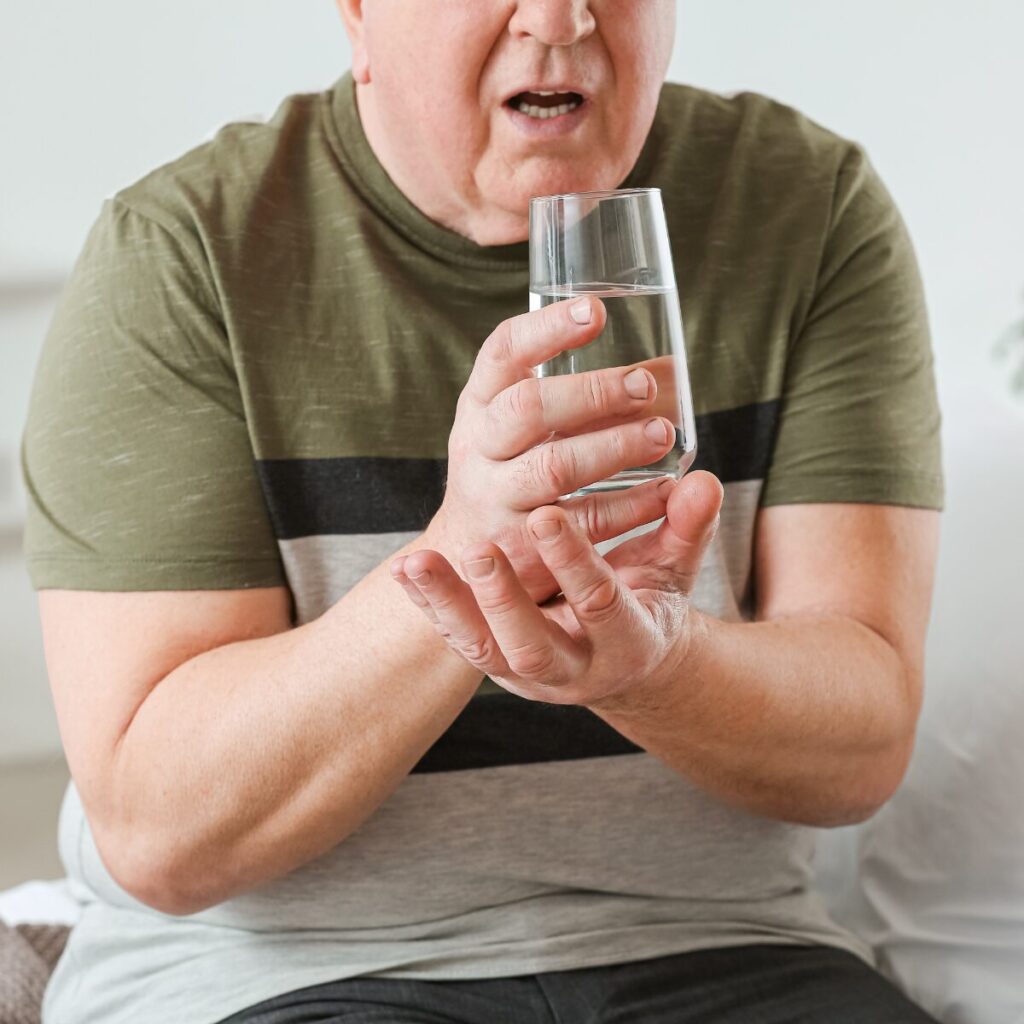 Man suffering from Parkinson's disease trying to drink water.