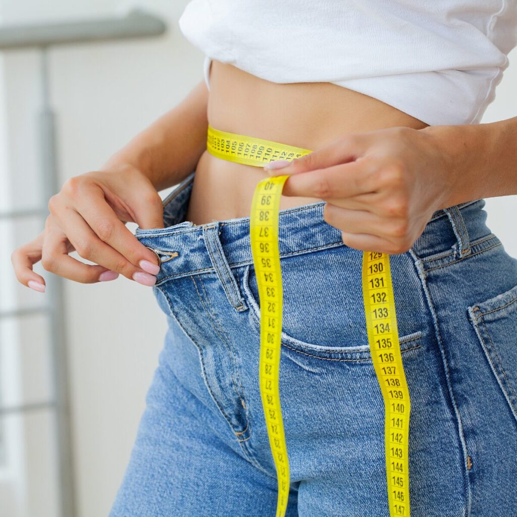 Woman measuring her waist with tape.