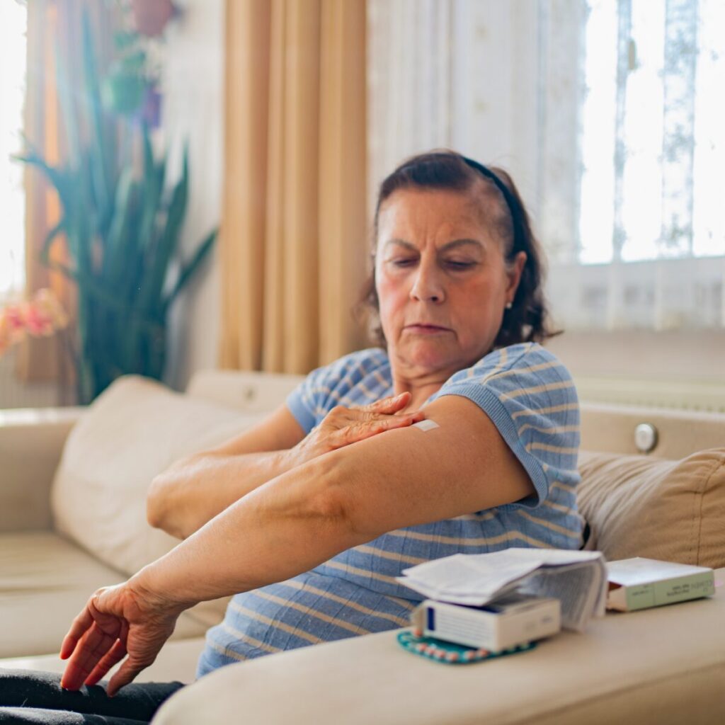 Woman applying Hormone replacement therapy patch on her arm.