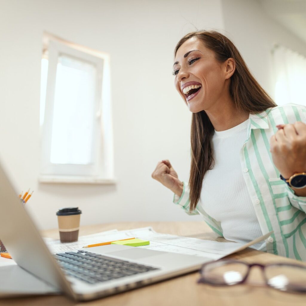 Woman excited and happy while working in front of laptop.